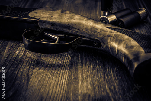 Hunting rifle with cartridges lying on a wooden table. Close up view © Georgii Shipin