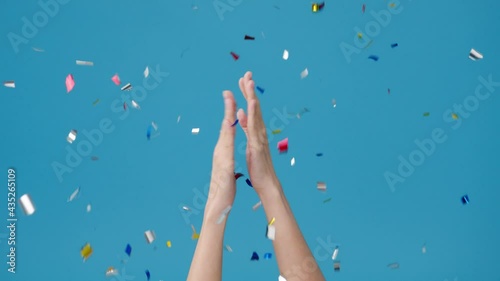 Young girl show hand clapping applause under confetti rain and celebrating over blue background. Copy space for place a text, message for advertisement. Advertising area, mock up promotional content.