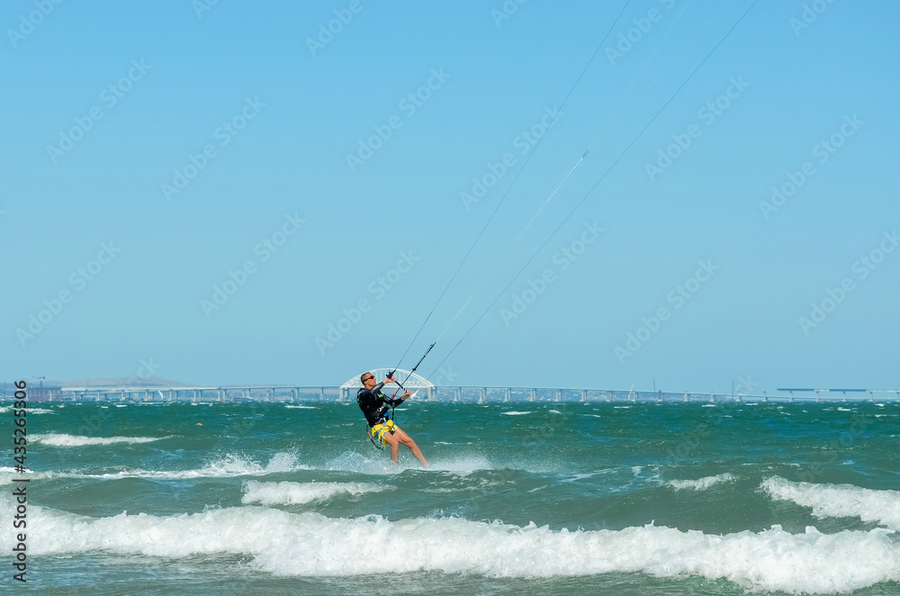 Kerch, Russia - 18 August 2020: Kite surfing on the blue sea in the background of blue sky at summer time. Kiteboarding. Fun in the ocean. Extreme Sport , surfing man