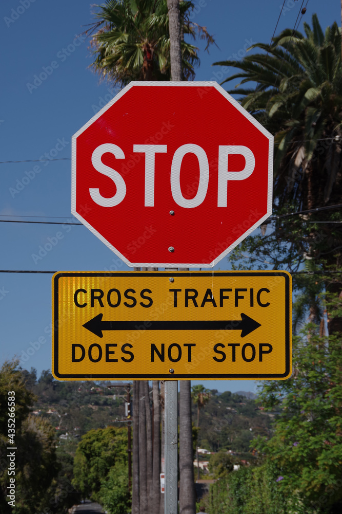City red traffic STOP sign with additional yellow sign CROSS TRAFFIC DOES NOT STOP