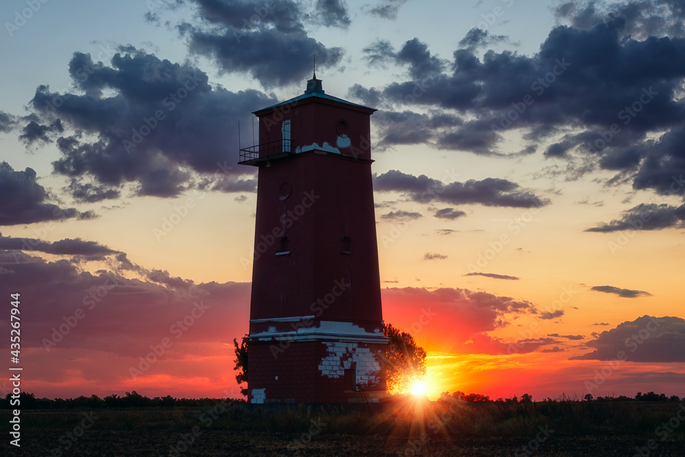 Khablovskiy lighthouse standing in the field at sunset, scenic landscape. Unique lighthouse on the border of Kherson and Mykolaiv region, Ukraine. Outdoor travel background with colorful dramatic sky