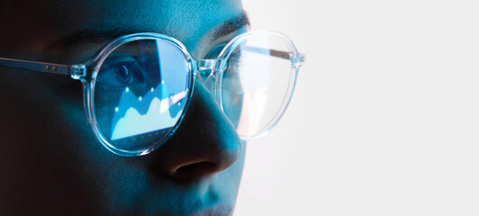 Close up view of blue eye in glasses with futuristic holographic interface to display data. Portrait of beautiful young woman, half of face. Augmented reality, future technology, internet concept.