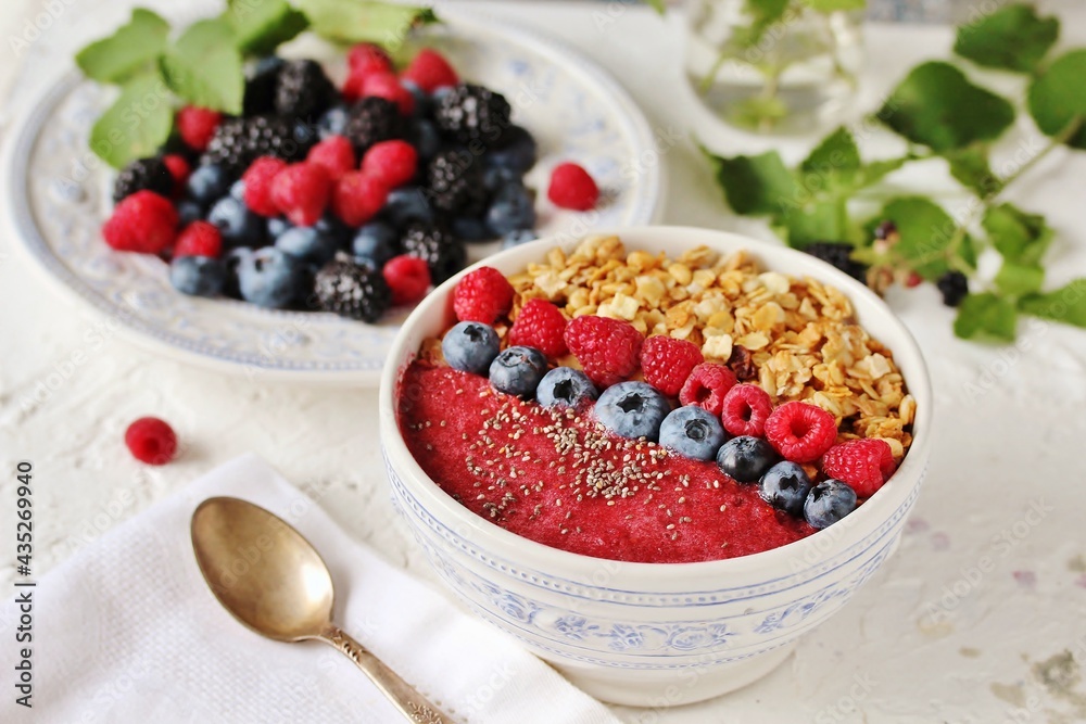 Colorful raspberry smoothie bowl with granola and fresh fruit, chia seeds. Breakfast berry smoothie bowl topped with blueberries, raspberry, blackberry, chia seeds, oat flakes and muesli. Colorful raspberry smoothie bowl with granola and fresh fruit, chia seeds. Breakfast berry smoothie bowl topped with blueberries, raspberry, blackberry, chia seeds, oat flakes and muesli.