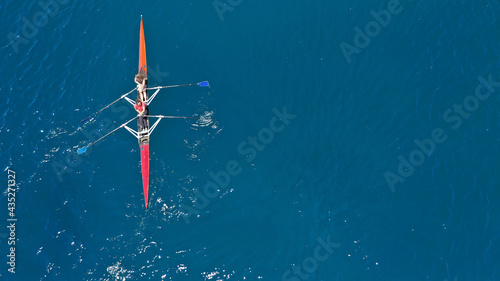 Aerial drone top down photo of sport canoe operated by team of young women in emerald calm sea waters