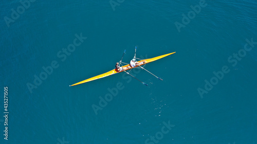 Aerial drone top down view of sport canoe operated by team of young trained athletes in deep blue Aegean sea