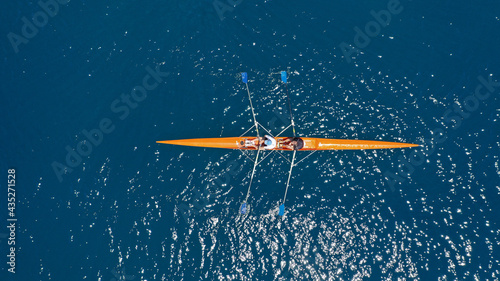 Aerial drone top down view of sport canoe operated by team of young trained athletes in deep blue Aegean sea