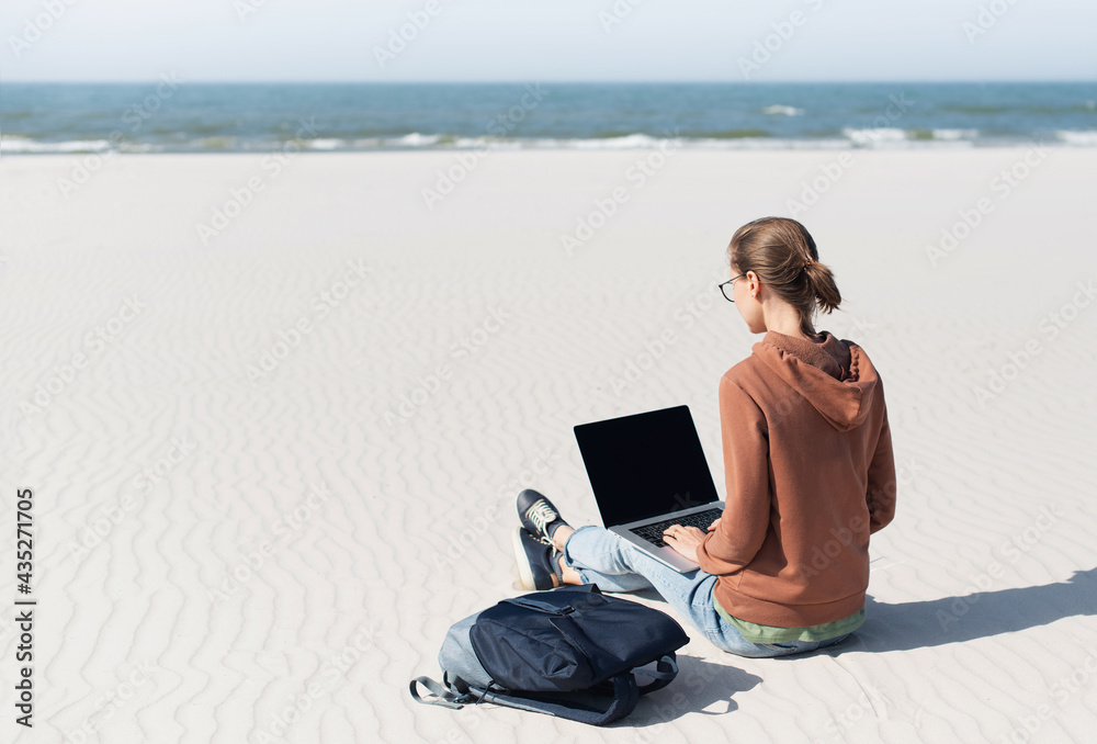 Woman using laptop computer on a beach. Freelance work, vacations, business, people, technologies, distance studying, e-learning, connection, social distancing, communication online concept.