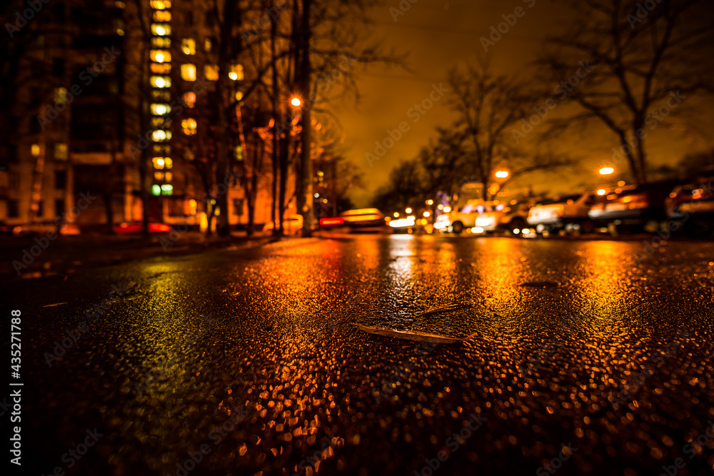 Rainy night in the big city, alley in the city. View from a wide angle at the level of asphalt