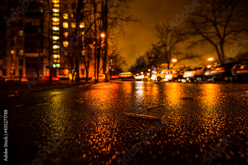 Rainy night in the big city, alley in the city. View from a wide angle at the level of asphalt