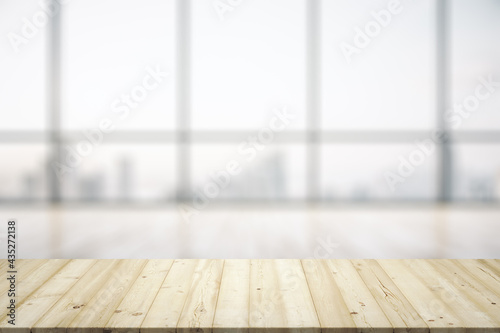 Empty wooden table with light sunny office interior with large window on background, mock up © Pixels Hunter