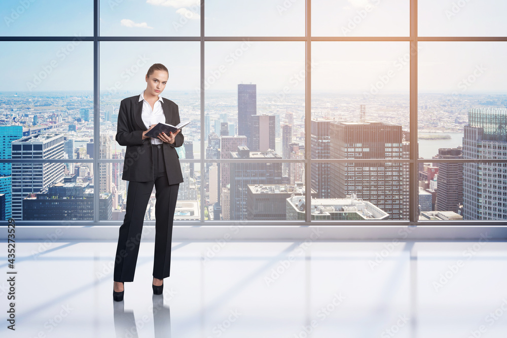Attractive businesswoman wearing formal suit holding her notes. Panoramic office on background with financial downtown city view. Attractive businesswoman wearing formal suit holding her notes. Panoramic office on background with financial downtown city view.
