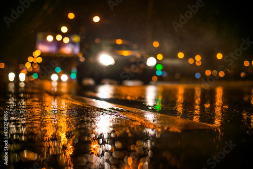 Rainy night in the big city, the light from the headlamps of approaching car on the highway. View from the level of the dividing line