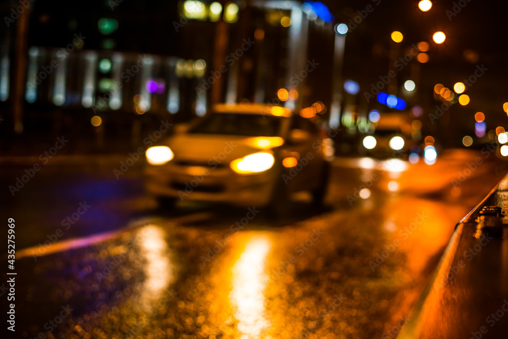 Rainy night in the big city, cars traveling on wet highway. View of the highway with a dividing border Rainy night in the big city, cars traveling on wet highway. View of the highway with a dividing border
