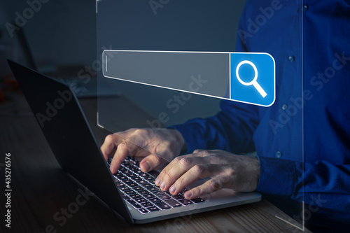 Searching on Internet with person using a browser software on laptop computer to open search engine with text bar and magnifying glass icon. Access information online.