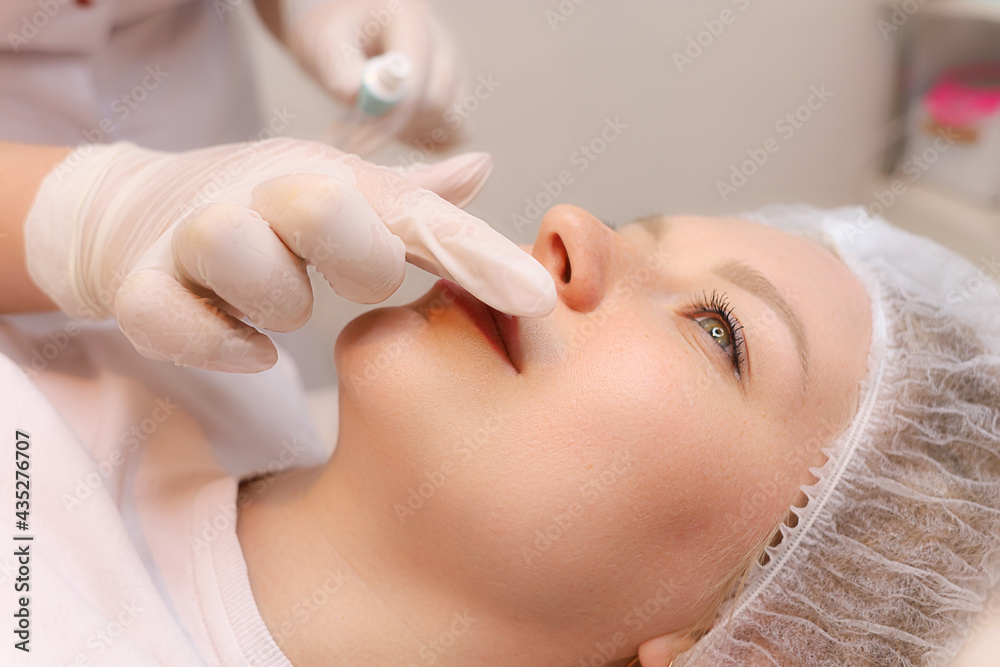 The cosmetologist prepares the client's lips for the augmentation procedure