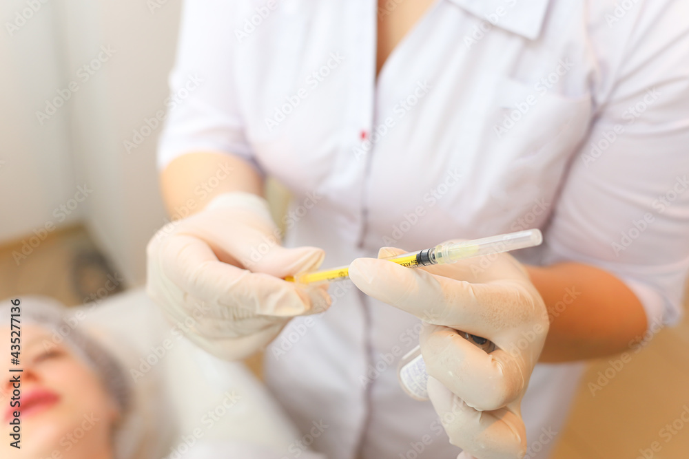 the cosmetologist holds a syringe in front of the client's face while preparing for the botox procedure the cosmetologist holds a syringe in front of the client's face while preparing for the botox procedure