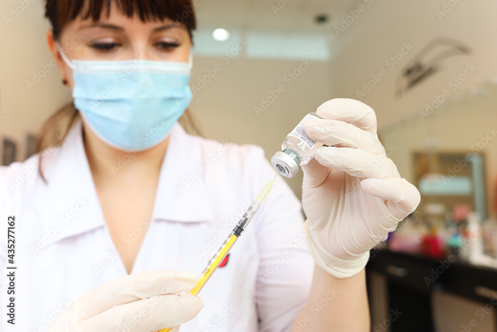 the cosmetologist holds a syringe with a bottle of the drug in front of him and draws a drug for beauty injections from it