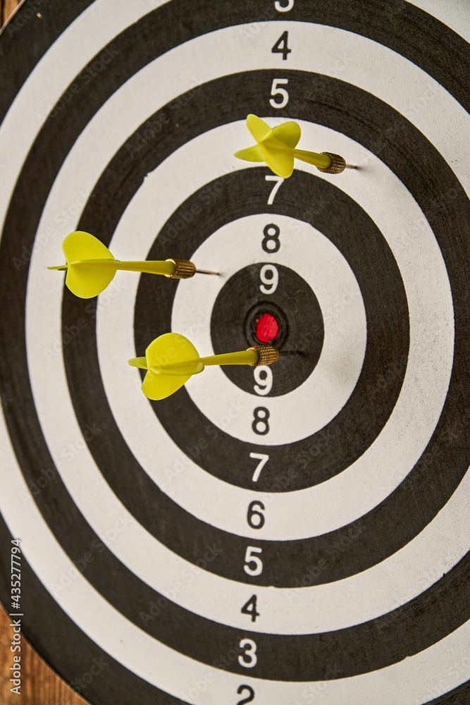 Darts game. Throwing darts at the target. Three yellow darts hit the target. Close-up Darts game. Throwing darts at the target. Three yellow darts hit the target. Close-up