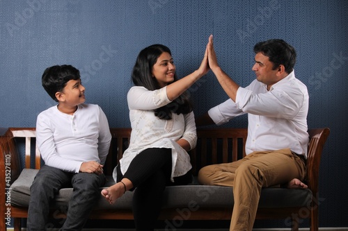 Portrait of Indian or Asian happy and young family, sitting over sofa at 