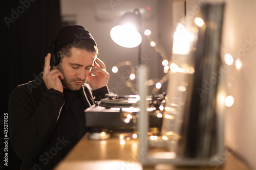 фотографія Young unshaven handsome hipster eyes closed guy listens to music with headphones