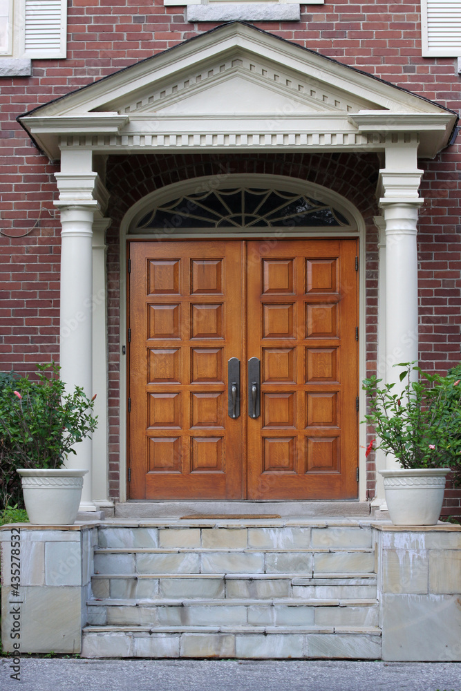 Elegant entrance with wood grain double door and portico
