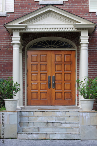 Elegant entrance with wood grain double door and portico