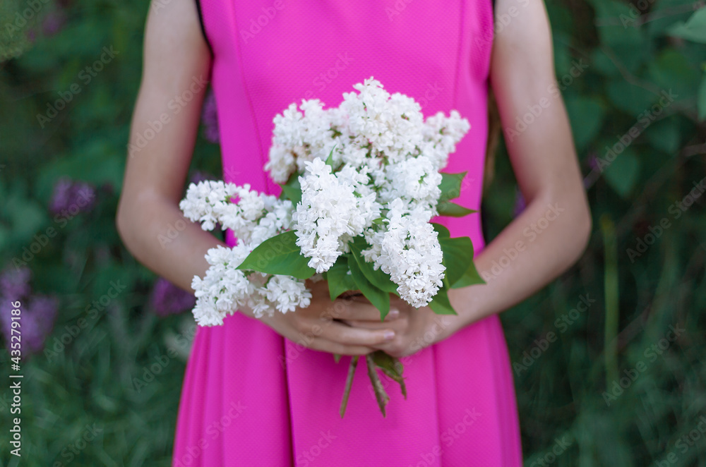 a girl in a purple dress holds a bouquet of white lilacs flowers