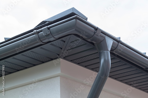 Fotografie Corner of house with new gray metal tile roof and rain gutter