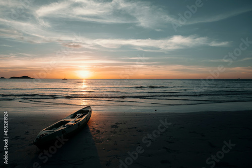 A kayak lies on the beach during a beautiful sunset. © De Visu