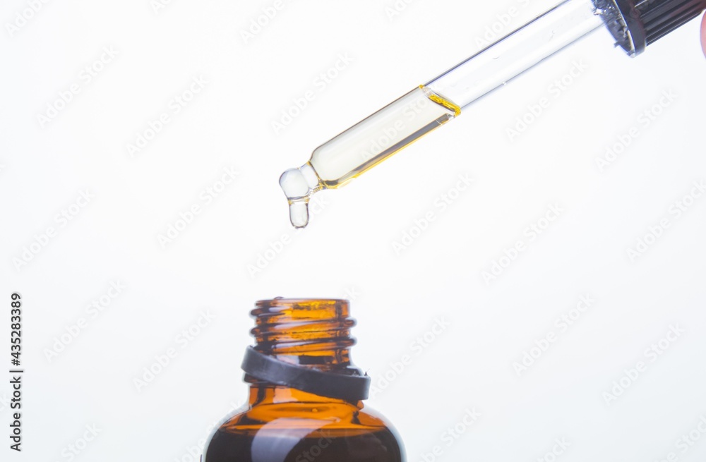 Drop falls from a pipette in a medical bottle close-up, isolated on a white background