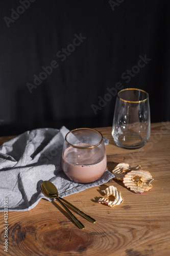 Glass of cocoa with golden spoon on wooden table 