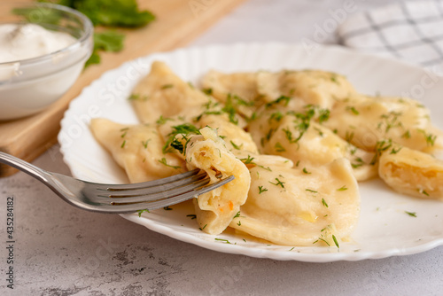 Potato dumplings sprinkled with dill on a white plate