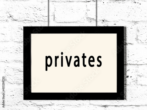 Black frame hanging on white brick wall with inscription privates
