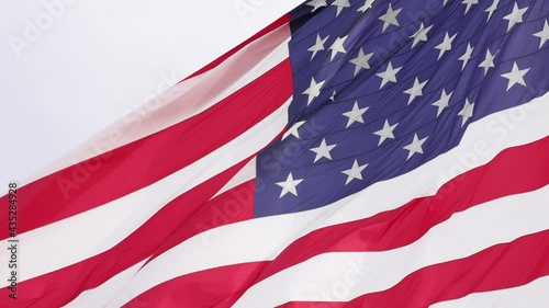 Close up american flag flying in strong wind slow motion.