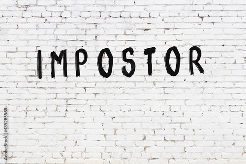 White wall with black paint inscription impostor on it photo