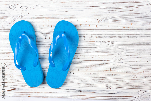 blue rubber slippers on a white wooden background, view from above, place under the text