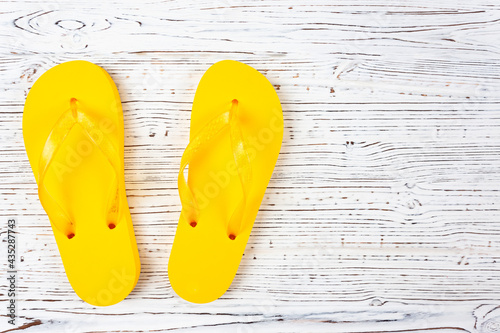 yellow rubber slippers on a white wooden background, view from above, place under the text