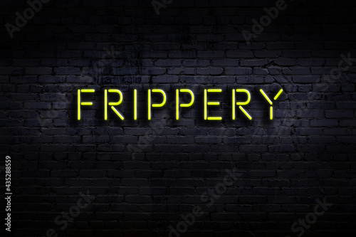 Neon sign. Word frippery against brick wall. Night view