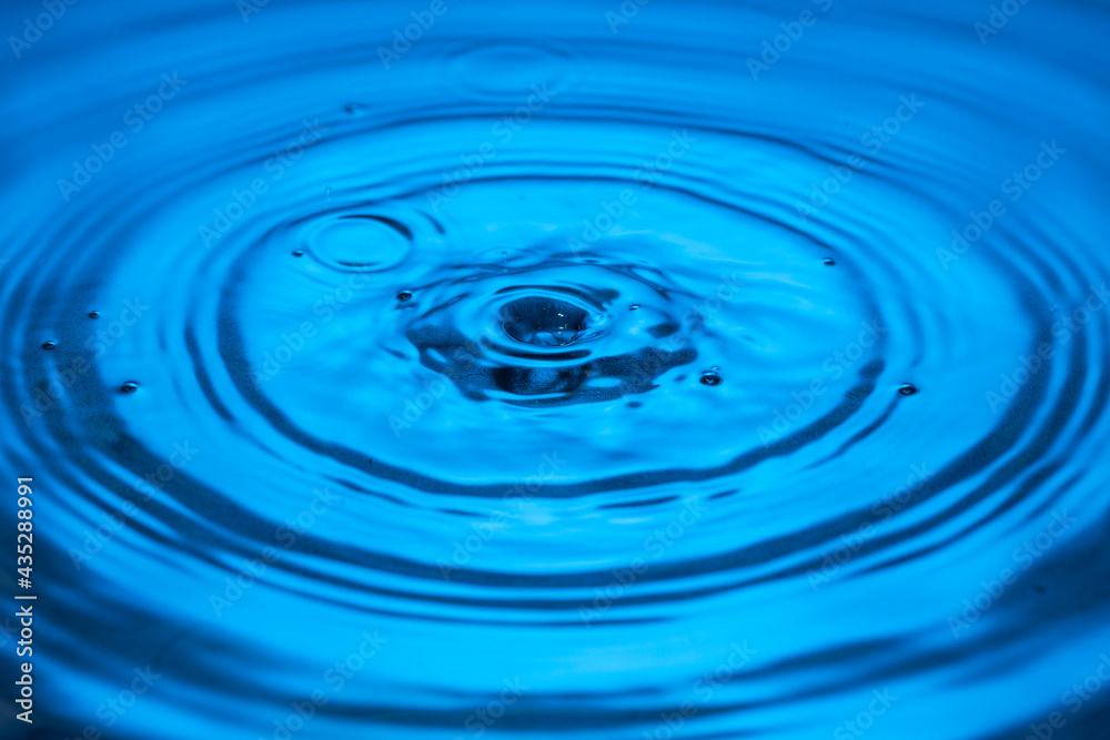 View of drops making circles on blue water surface isolated on background. View of drops making circles on blue water surface isolated on background.
