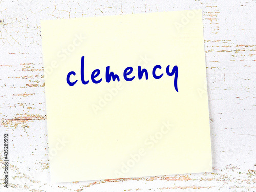 Photography Yellow sticky note on wooden wall with handwritten word clemency
