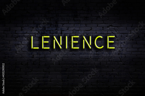 Night view of neon sign on brick wall with inscription lenience photo