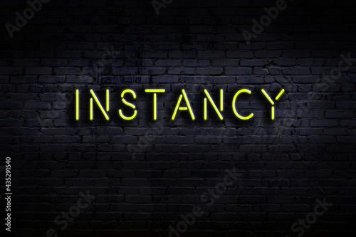 Night view of neon sign on brick wall with inscription instancy photo