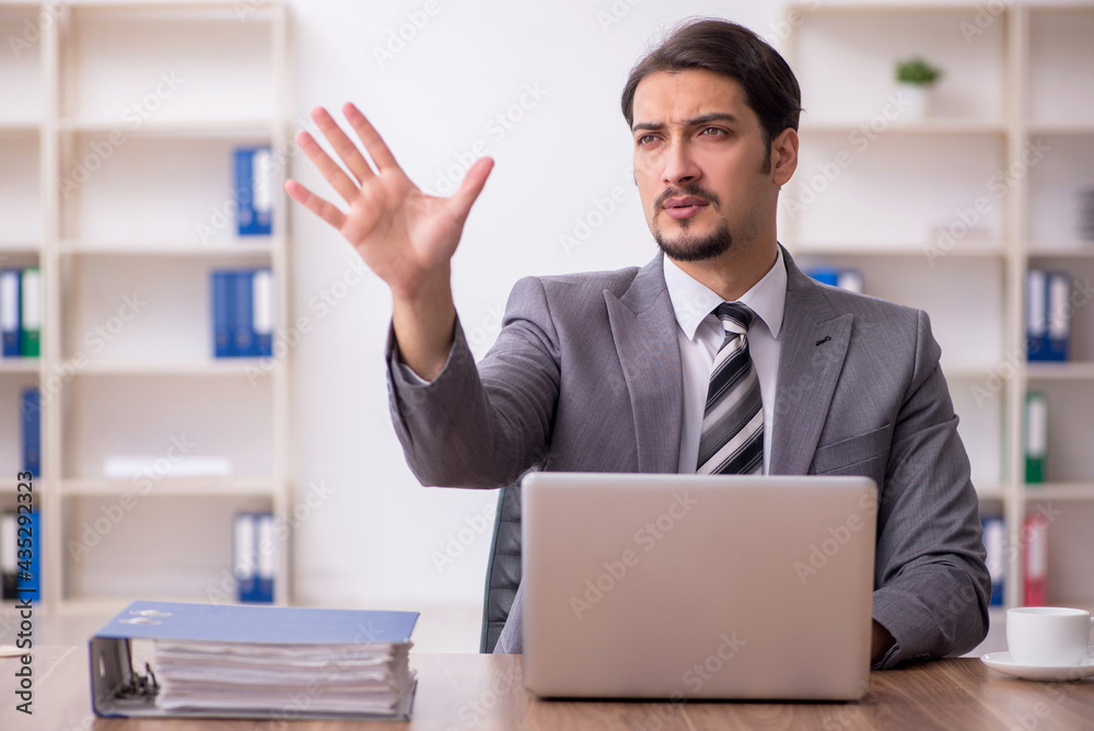 Young attractive male employee sitting at workplace Young attractive male employee sitting at workplace