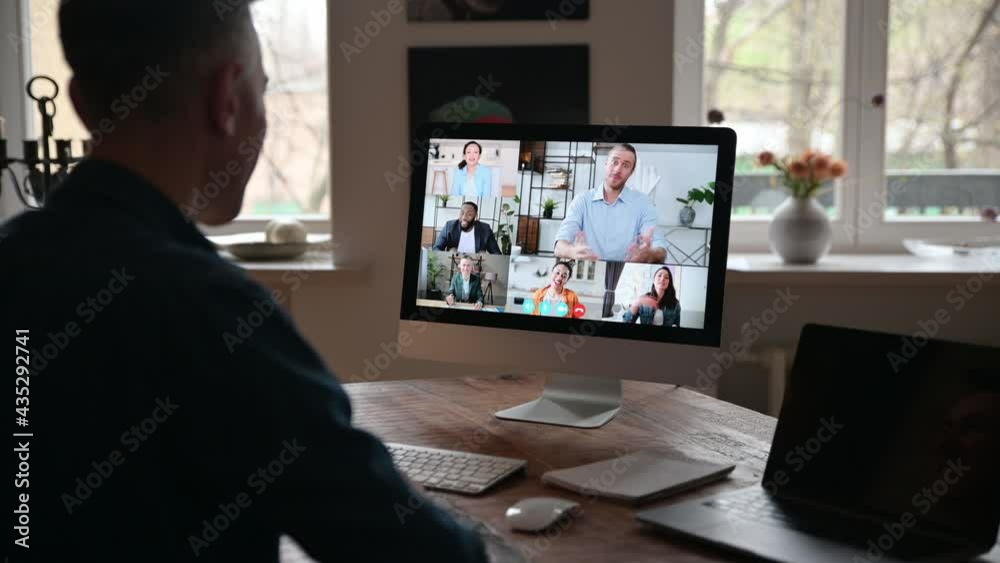 Online communication. View over a man's shoulder at a computer screen with diverse business people gathered in a group online conference to discuss work issues and business strategy and plans Online communication. View over a man's shoulder at a computer screen with diverse business people gathered in a group online conference to discuss work issues and business strategy and plans