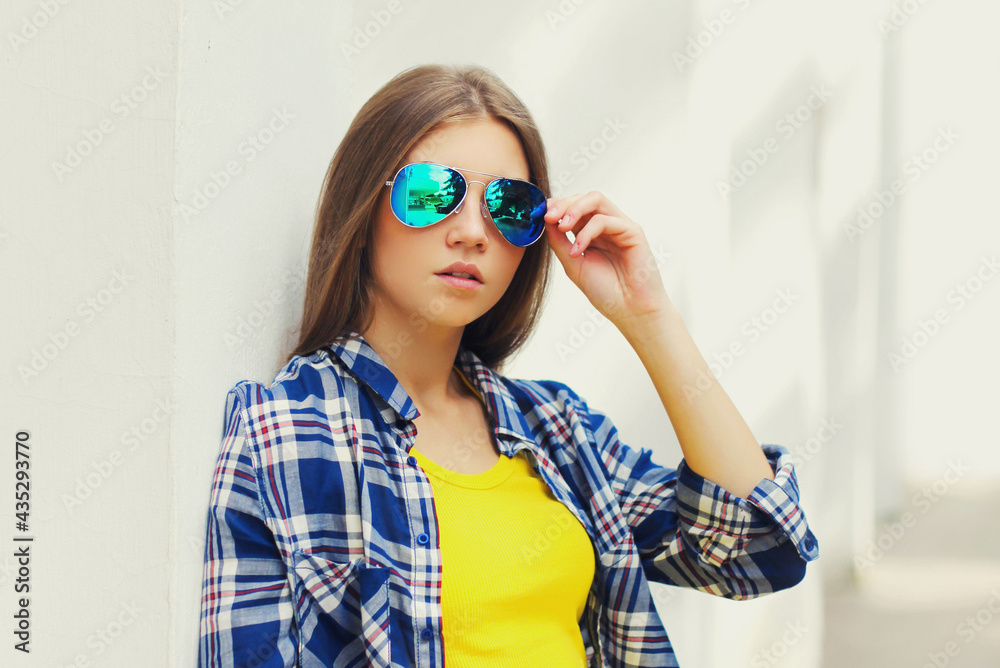 Fototapeta premium Portrait close up of beautiful young woman wearing a sunglasses posing in a city