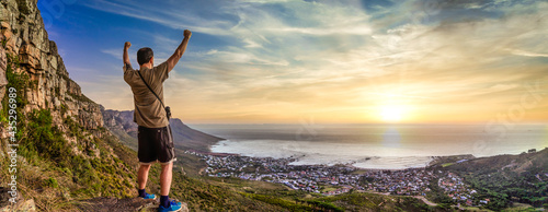 Victory and success after a hike up Table Mountain at sunset. Looking over the bay with a vibrant orange sky - Great outdoors adventure and travel holiday destination, Cape Town, South Africa