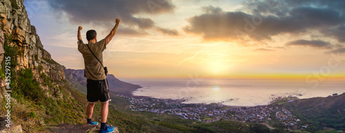 Victory and success after a hike up Table Mountain at sunset with vibrant orange sky - looking out over the bay - Great outdoors adventure and travel holiday destination, Cape Town, South Africa