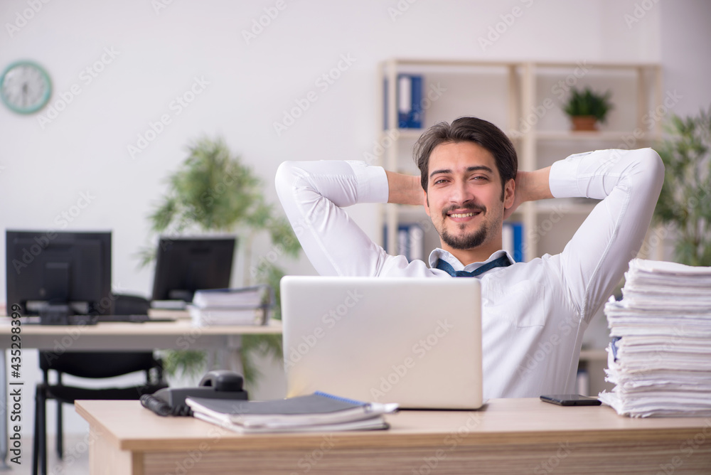 Young male employee unhappy with excessive work in the office Young male employee unhappy with excessive work in the office