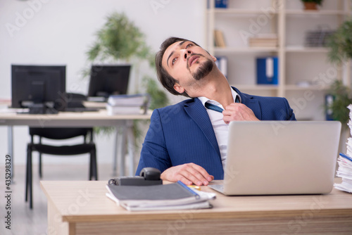 Young male employee unhappy with excessive work in the office