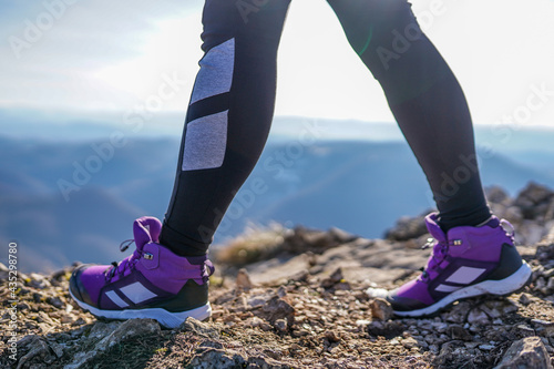 Close up of woman's legs with leggings and hiking shoes on top of the mountain